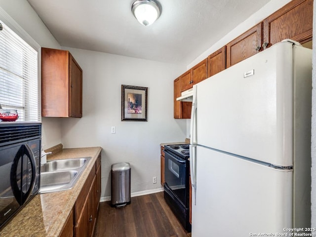 kitchen with brown cabinetry, under cabinet range hood, dark wood-style floors, black appliances, and a sink