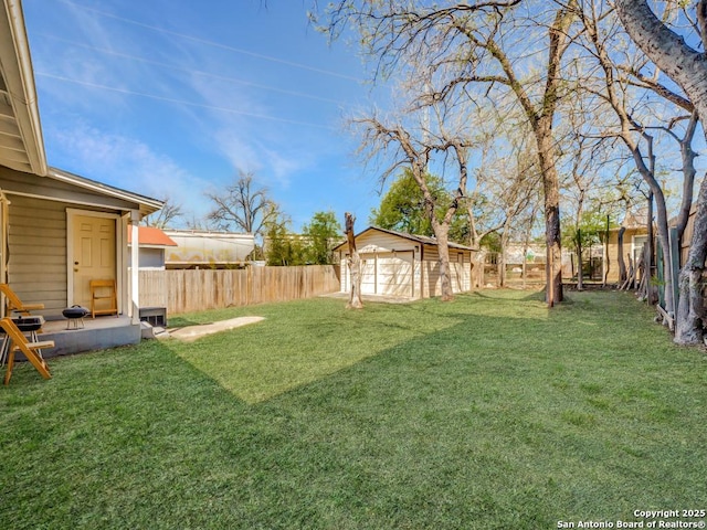 view of yard with a garage, an outbuilding, and a fenced backyard