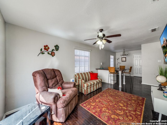 living area featuring wood finished floors and ceiling fan with notable chandelier