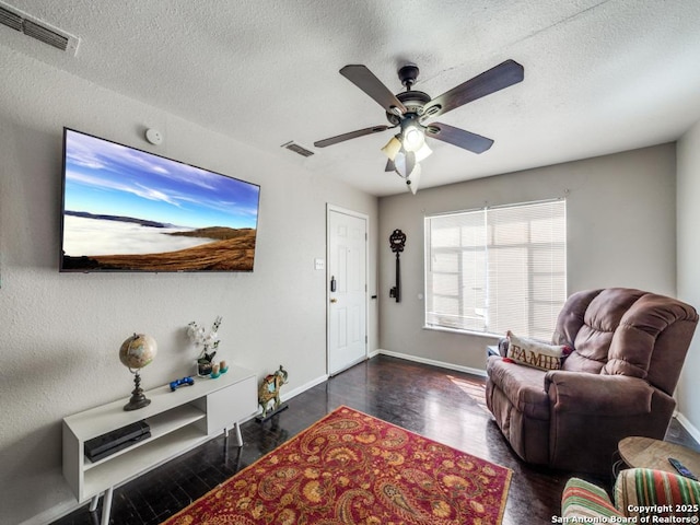 living area with visible vents, a textured ceiling, ceiling fan, and wood finished floors