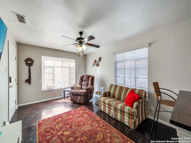 living area with visible vents, baseboards, ceiling fan, wood finished floors, and a textured ceiling