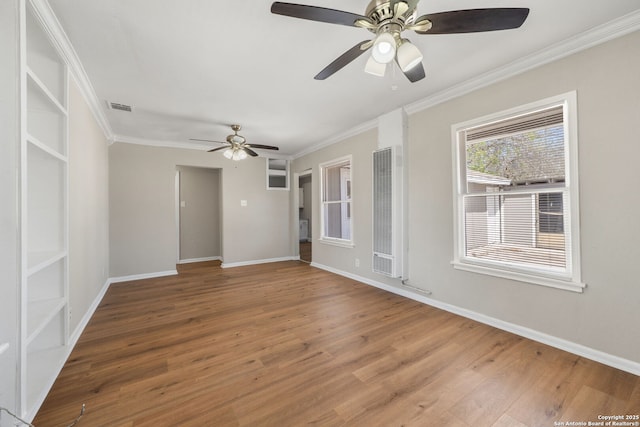 empty room featuring crown molding, wood finished floors, visible vents, and ceiling fan