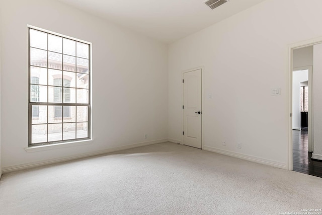 carpeted spare room featuring baseboards and visible vents