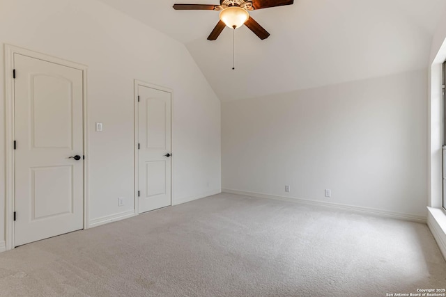 interior space with carpet floors, baseboards, ceiling fan, and vaulted ceiling