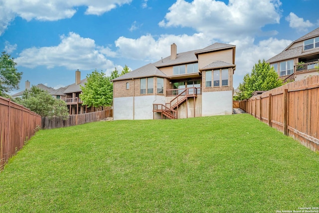back of property with a fenced backyard, stairs, and a yard