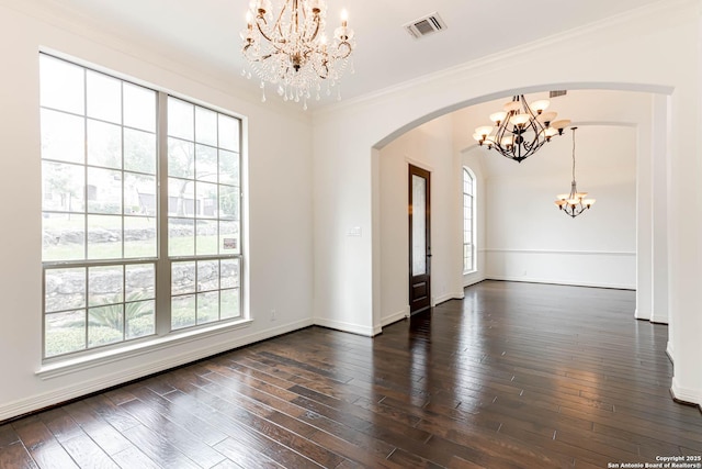 empty room featuring visible vents, ornamental molding, dark wood-style floors, a chandelier, and arched walkways