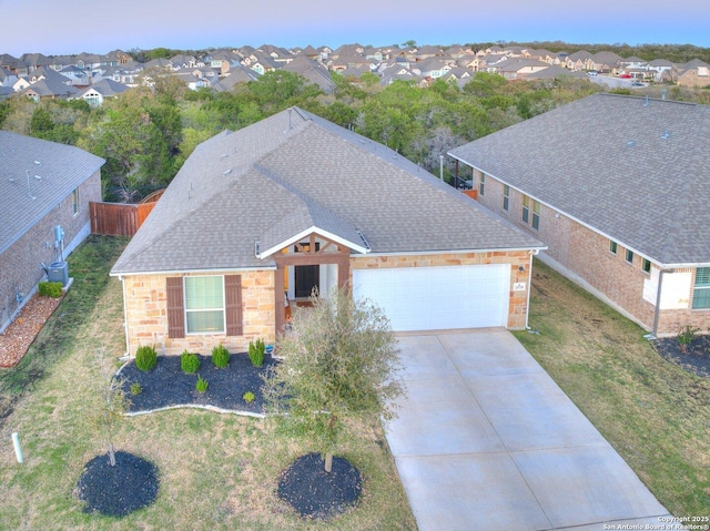 view of front of home with stone siding, a garage, concrete driveway, a front lawn, and a shingled roof