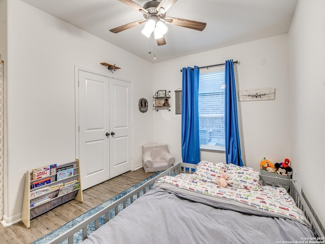 bedroom with a closet, baseboards, wood finished floors, and a ceiling fan