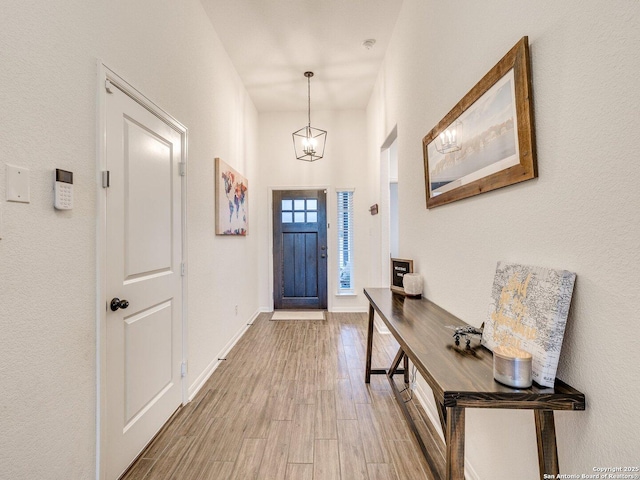entrance foyer featuring a notable chandelier, baseboards, and wood finished floors