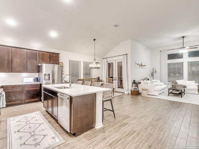 kitchen with open floor plan, french doors, stainless steel appliances, a breakfast bar, and a sink