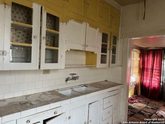 632 Canton, San Antonio, TX 78202 - kitchen with tile countertops, decorative backsplash, white cabinets, and a sink