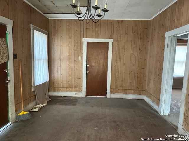 632 Canton, San Antonio, TX 78202 - unfurnished dining area featuring baseboards, a chandelier, and wood walls