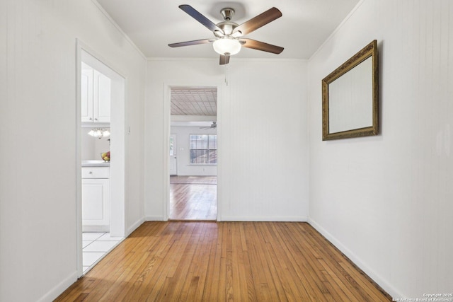 spare room with light wood-style flooring, baseboards, ceiling fan, and ornamental molding