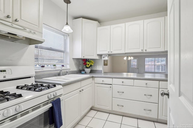 kitchen with under cabinet range hood, a sink, white cabinets, white gas range, and hanging light fixtures