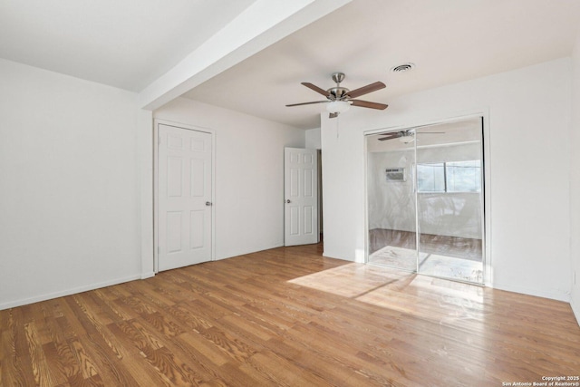unfurnished bedroom featuring ceiling fan, visible vents, baseboards, and wood finished floors