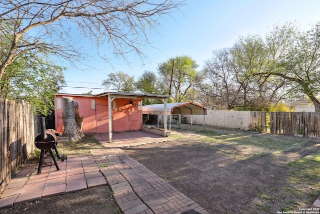 view of yard with a carport, a storage shed, an outbuilding, and a fenced backyard
