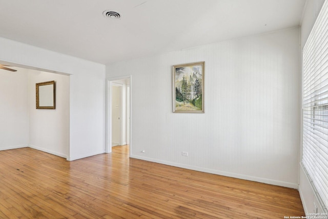 spare room featuring a ceiling fan, light wood-style floors, visible vents, and baseboards