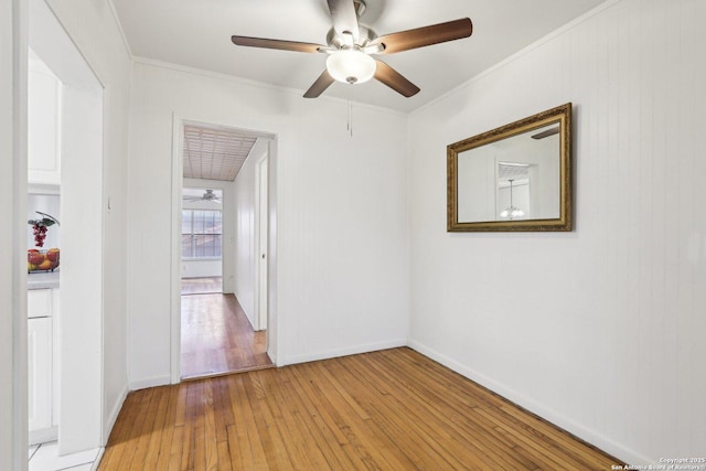 spare room with ornamental molding, baseboards, light wood-type flooring, and ceiling fan