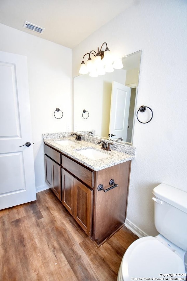 10314 Candlewood Way, San Antonio, TX 78245 - bathroom featuring wood finished floors, toilet, double vanity, and baseboards