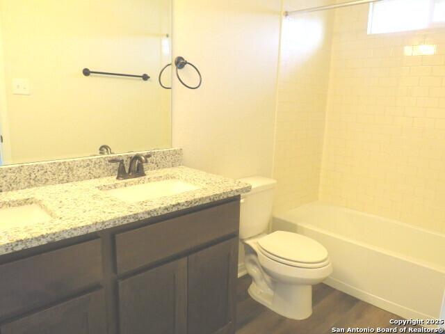 10314 Candlewood Way, San Antonio, TX 78245 - bathroom featuring toilet, wood finished floors, double vanity, and bathing tub / shower combination