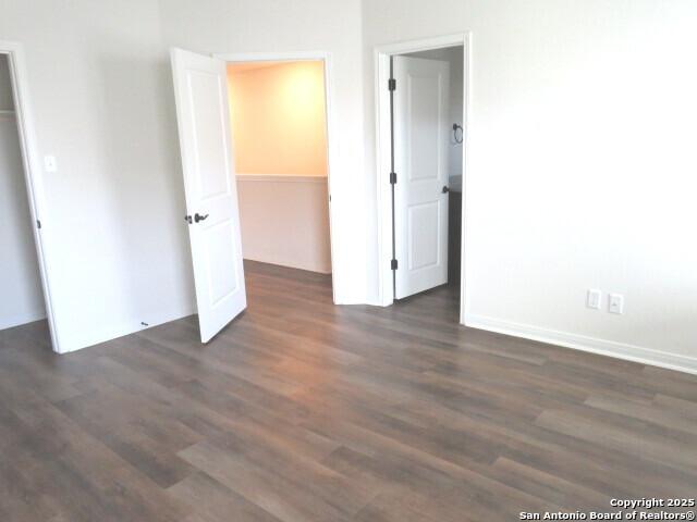 10314 Candlewood Way, San Antonio, TX 78245 - unfurnished bedroom with a walk in closet, dark wood-style floors, and a closet