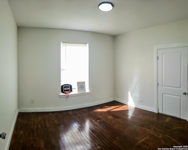 spare room featuring baseboards and wood-type flooring