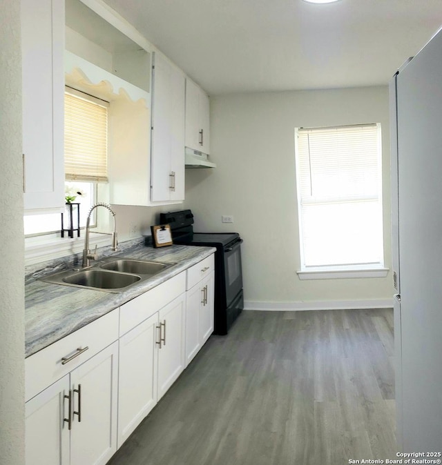 kitchen with under cabinet range hood, light countertops, black electric range oven, white cabinetry, and a sink