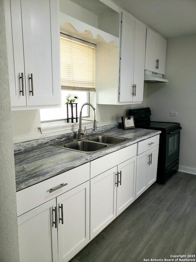kitchen featuring electric range, under cabinet range hood, a sink, white cabinets, and dark wood-style flooring