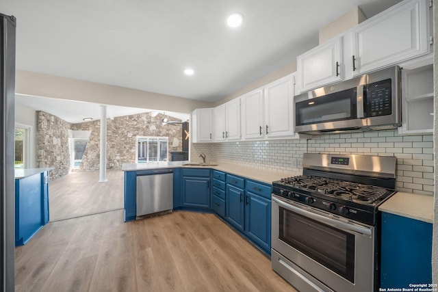 kitchen with light countertops, white cabinets, stainless steel appliances, blue cabinets, and a sink