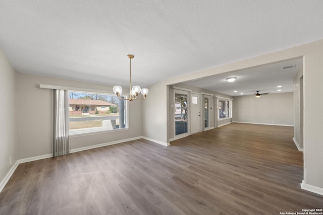 unfurnished room featuring visible vents, ceiling fan with notable chandelier, baseboards, and wood finished floors