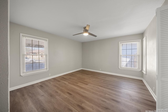 unfurnished room with baseboards, a healthy amount of sunlight, wood finished floors, and a ceiling fan