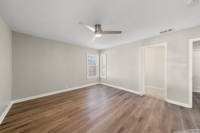 unfurnished bedroom featuring ceiling fan, visible vents, baseboards, and wood finished floors