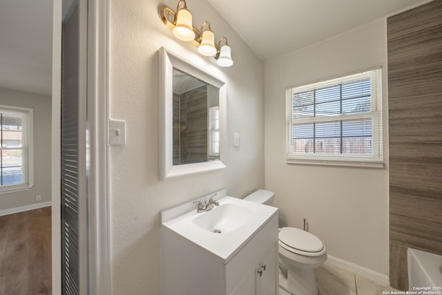 full bath with a tub, toilet, vanity, and baseboards