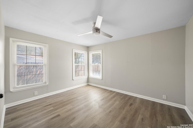 unfurnished room with a ceiling fan, wood finished floors, and baseboards