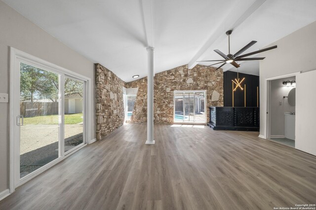 unfurnished living room with vaulted ceiling with beams, ornate columns, a fireplace, wood finished floors, and a ceiling fan