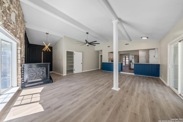 unfurnished living room featuring lofted ceiling with beams, visible vents, a healthy amount of sunlight, and light wood finished floors