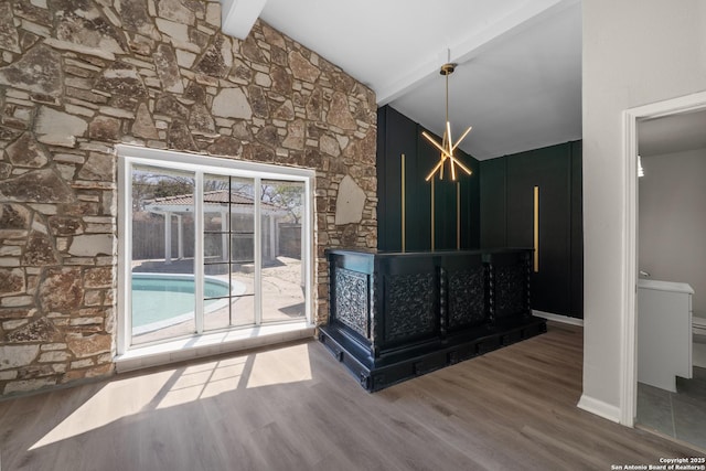 interior space featuring lofted ceiling with beams, baseboards, and wood finished floors