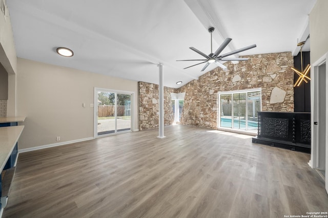 unfurnished living room featuring wood finished floors, a ceiling fan, lofted ceiling with beams, decorative columns, and a fireplace