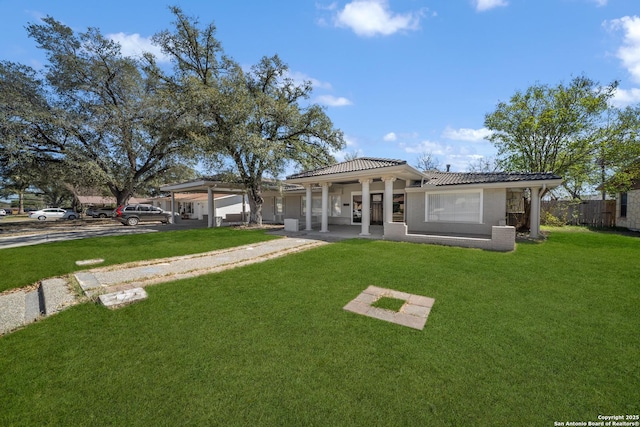 rear view of property with fence, a tiled roof, stucco siding, a lawn, and an attached garage