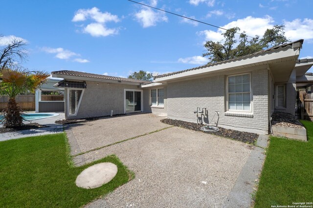 rear view of property with brick siding, a fenced in pool, a patio, and fence