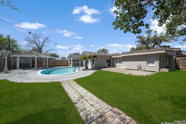 back of property with a lawn, a patio, a fenced backyard, and a fenced in pool