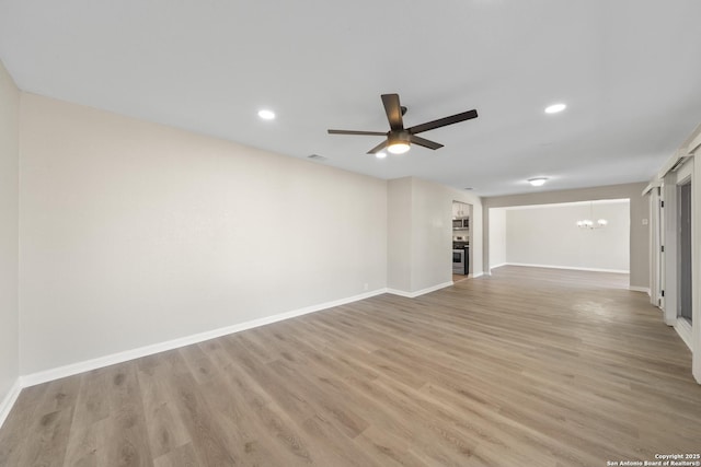 unfurnished living room with light wood-type flooring, visible vents, ceiling fan with notable chandelier, recessed lighting, and baseboards