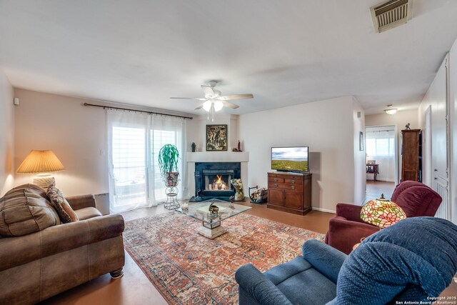 12938 Ocean Glade, San Antonio, TX 78249 - living area featuring a warm lit fireplace, visible vents, baseboards, and a ceiling fan