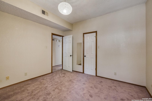 8633 Datapoint Unit 227, San Antonio, TX 78229 - unfurnished bedroom with light carpet, baseboards, a textured ceiling, and a chandelier