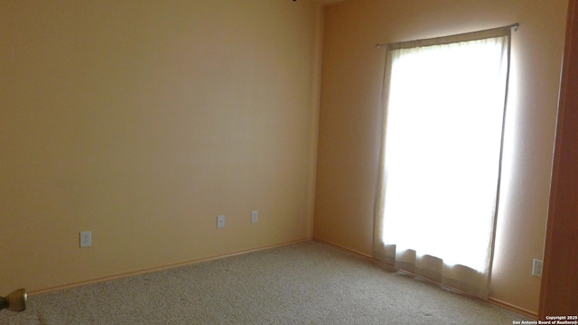 spare room featuring baseboards and light colored carpet