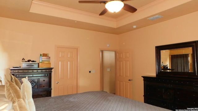 bedroom with a ceiling fan, ornamental molding, visible vents, and a raised ceiling