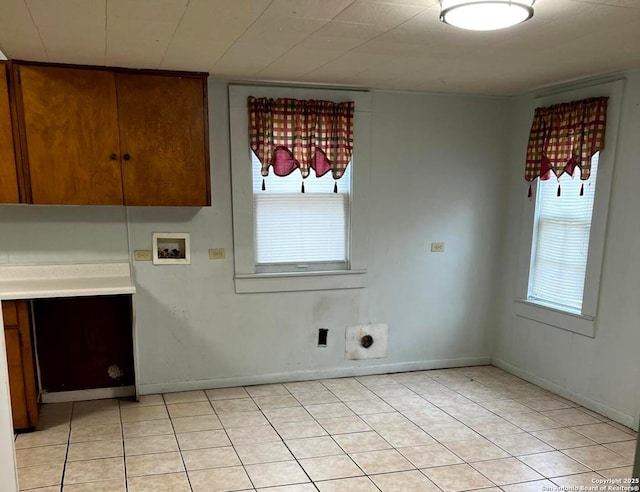 clothes washing area with cabinet space, light tile patterned floors, hookup for a washing machine, and baseboards