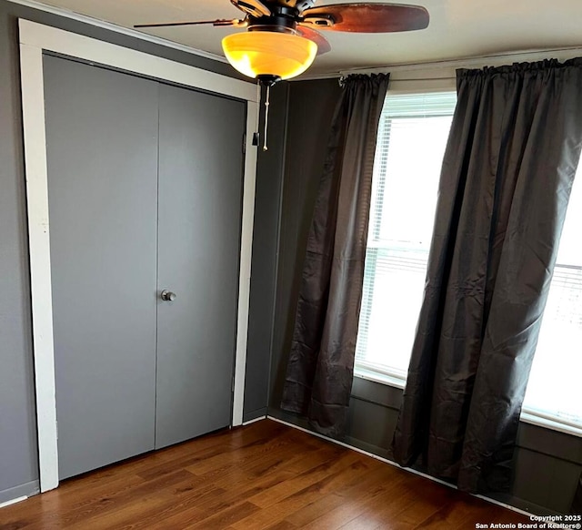 unfurnished bedroom with multiple windows, ceiling fan, and wood finished floors