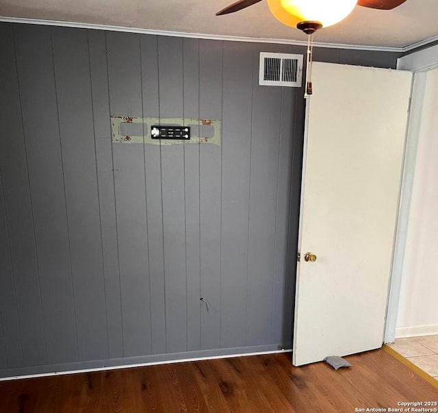 room details with visible vents, ornamental molding, ceiling fan, and wood finished floors