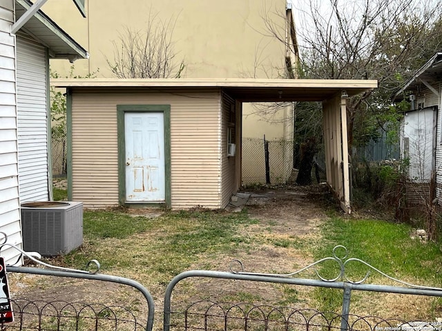 view of outbuilding featuring an outdoor structure, fence, and central AC